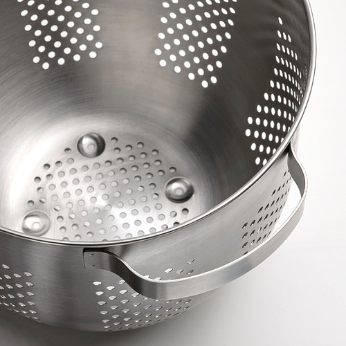 Colador de acero inoxidable con gotas de agua caídas, que muestra su calidad limpia y duradera.