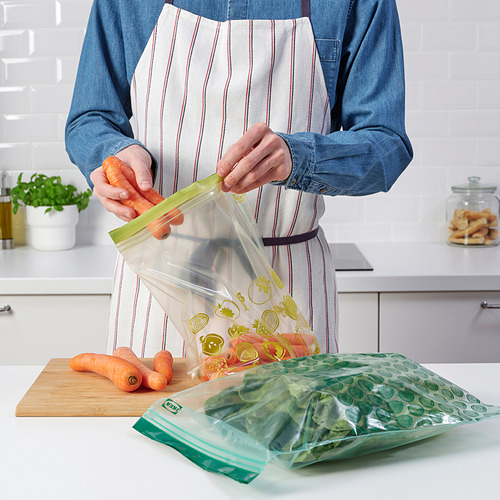Mujer preparando verduras con bolsas reutilizables con cierre hermético en la cocina.