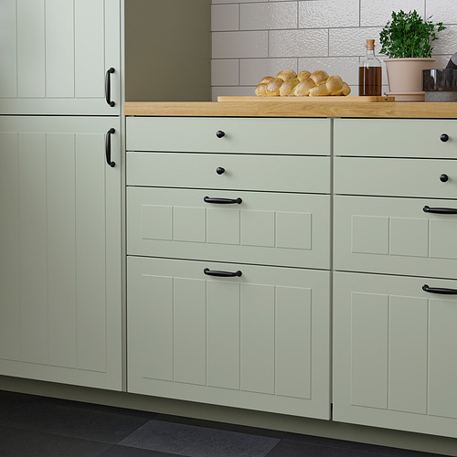 Armarios de cocina STENSUND de color verde claro con encimera de madera. Incluye cajones y pan, plantas y botella en la parte superior.