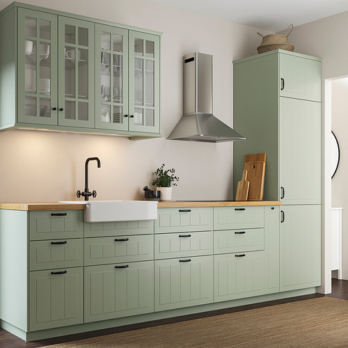 Cocina moderna con grandes gabinetes de color verde claro, encimera de madera, campana y fregadero de acero inoxidable. Los armarios altos llegan hasta el techo.