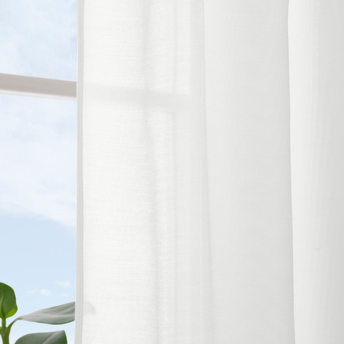 Cortinas blancas transparentes cuelgan de una ventana, difundiendo la luz solar y asegurando la privacidad durante el día.
