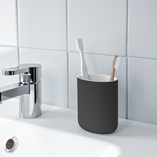 Baño moderno con grifo cromado, soporte para cepillos de dientes gris y dos cepillos de dientes sobre encimera blanca. EKOLN.