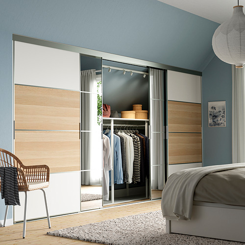 Dormitorio moderno azul con cama gris, puerta de armario con espejo SKYTTA, ropa a la vista.