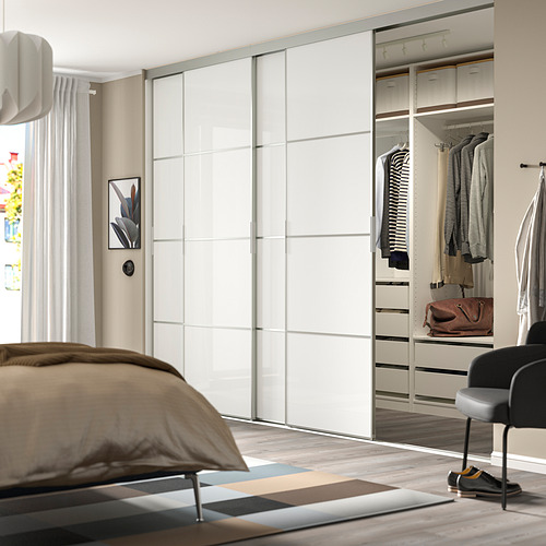 Dormitorio moderno con un gran armario con espejos, ropa cuidadosamente dispuesta e iluminación suave.