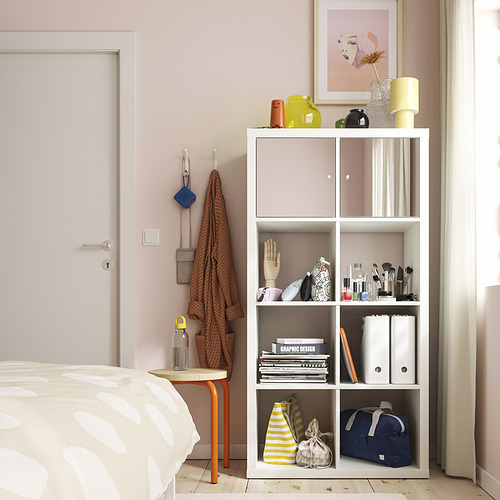 Dormitorio moderno con paredes rosas, gancho SNÖRAKA con bufanda, estantería y una cama con edredón estampado.