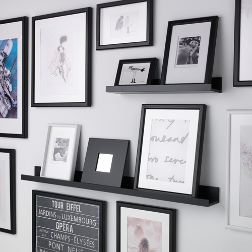 Estante de exhibición de pared con múltiples marcos de fotos, que muestran fotos y arte.