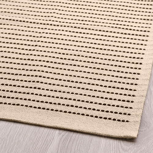Alfombra beige con rayas marrones, cuidadosamente colocada sobre suelo de madera, con una textura de algodón de alta calidad y costuras uniformes.