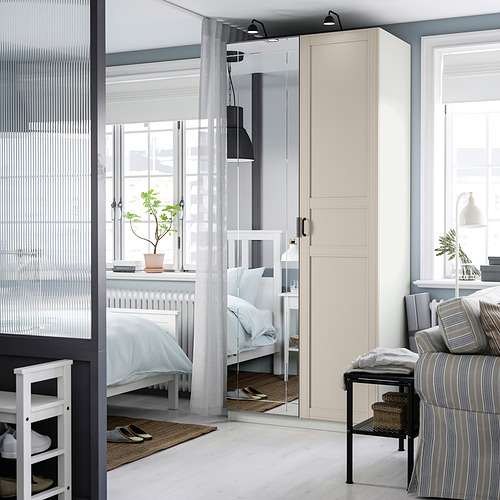 Dormitorio moderno con armario PAX, puertas con espejos y almohadas a rayas.