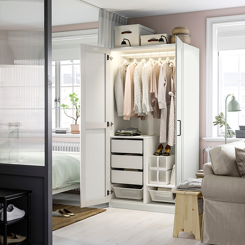 Habitación moderna con armario PAX blanco, puerta con espejo y almacenamiento organizado.