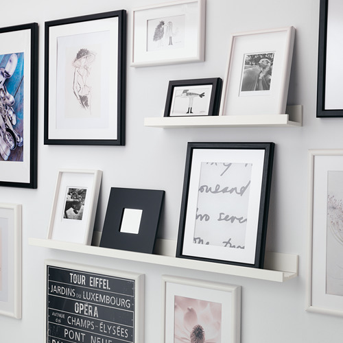 Estantería de pared con marcos de fotos variados; objetos personales y obras de arte.