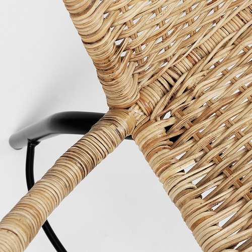 Detalle de silla de ratán tejido, color natural con estructura de metal negro, elaborada por expertos.