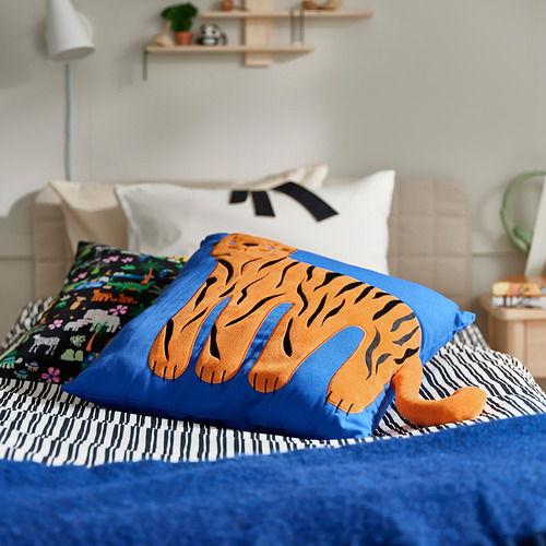 Cama con cojín de tigre azul, manta a rayas y almohada de colores.