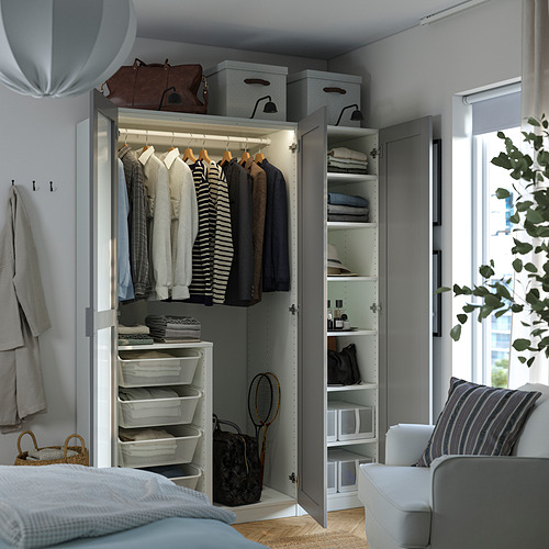 Open wardrobe displaying clothes on hangers, folded clothes, and storage bins; mirror on left door.