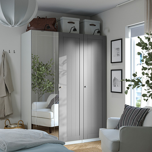Modern bedroom: grey wardrobe, mirrored door, white chairs, plants, wall art.