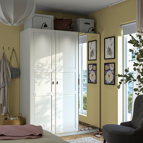 Habitación bien organizada con armario blanco PAX, puertas con espejos, elementos decorativos y luz natural.