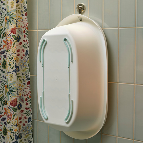 Bañera blanca para bebés con bordes suaves cuelga de la pared de azulejos, cortina floral cerca.