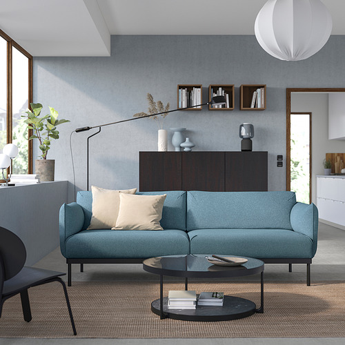 Sala de estar contemporánea con sofá ÄPPLARYD verde azulado, mesa de centro negra y decoración minimalista.