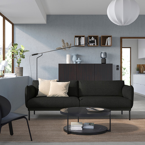 Sala de estar moderna con sofá ÄPPLARYD gris, mesa de centro negra, aparador de madera y lámpara colgante.