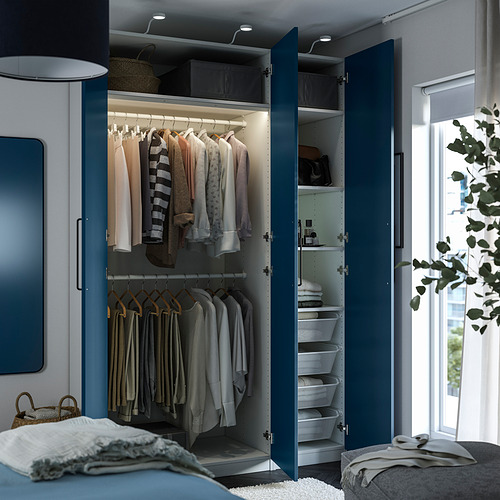 Un armario moderno con puertas azules que se abren, revelando ropa colgada, estantes y cestas, diseñado para maximizar el espacio de almacenamiento.