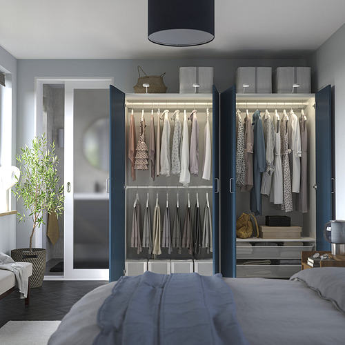 Dormitorio con armario abierto que muestra ropa, estanterías y accesorios. El armario tiene luces internas y almacenamiento ajustable.
