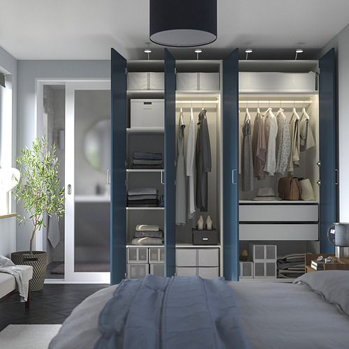 Dormitorio moderno con armario PAX con ropa gris, toallas dobladas e iluminación exterior.