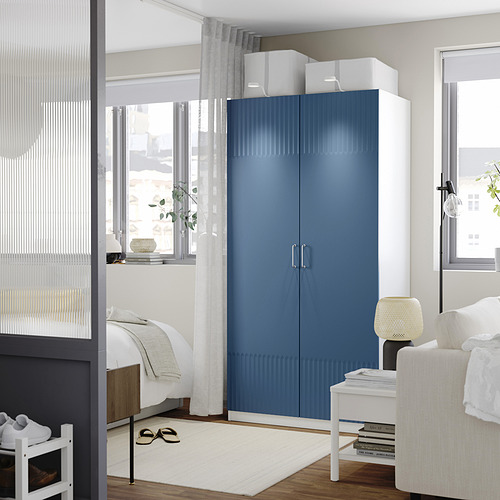 Dormitorio moderno con gran armario azul oscuro, cama blanca y decoración minimalista.