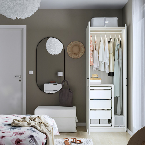 Dormitorio minimalista con armario PAX, lámpara colgante, espejo y cama con manta floral.