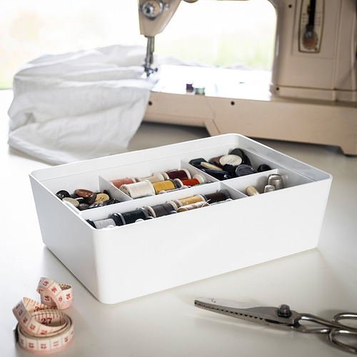 La caja blanca de KUGGIS organiza botones, hilos y accesorios, con tijeras y cinta adhesiva.