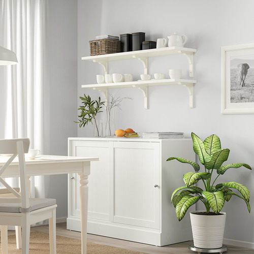 Estante blanco BERGSHULT con tazas, libros y plantas debajo.