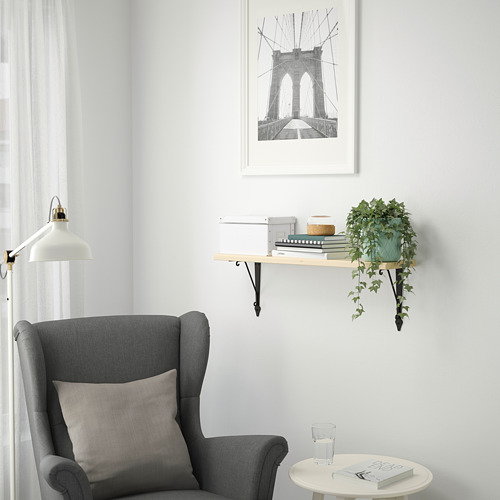 Acogedor rincón con sillón gris, mesa auxiliar, libros, planta, estampado puente brooklyn.