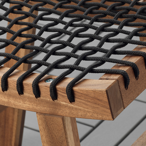 Primer plano del elegante y robusto taburete de madera de acacia con un intrincado asiento negro trenzado, que muestra una artesanía de alta calidad.