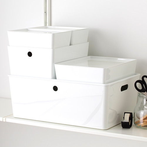 Cajas de almacenamiento de plástico blanco apiladas con tapas en el estante, protegen los artículos del polvo.