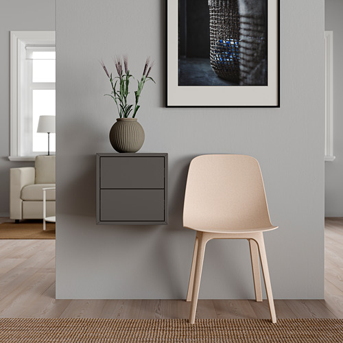 Rincón de habitación minimalista con silla blanca, armario EKET gris, planta y arte enmarcado.
