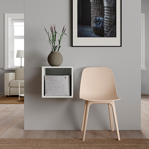 Combo minimalista de silla y estantería: silla de color claro, estantería blanca de pared con cajón gris, planta en jarrón beige, arte abstracto.