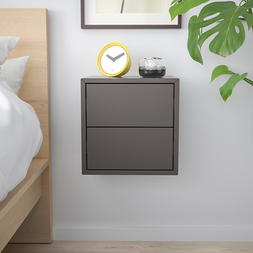 Dormitorio minimalista con gabinete EKET gris oscuro, planta y reloj.