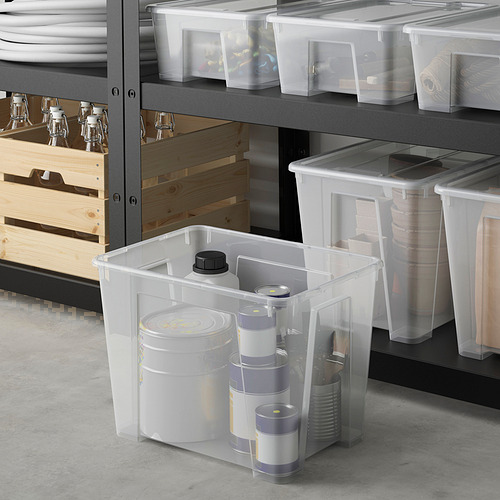 Área de almacenamiento con cajas SAMLA de diferentes tamaños, artículos de limpieza en los más grandes, estantes con artículos más pequeños, cajas de madera y platos.