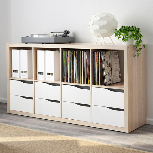 Estantería de madera KALLAX con cajones, que contiene discos de vinilo y decoración para el hogar.