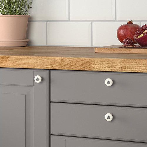 Cajón de cocina gris con tapa de madera, pomos KLINGSTORP, planta en maceta y granadas.
