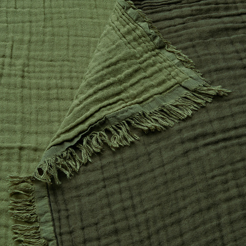 Manta verde suave con bordes de flecos, textura de algodón arrugado.
