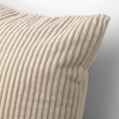 Cojín de pana beige suave, cuidadosamente doblado contra una pared azul claro, que luce su diseño texturizado.