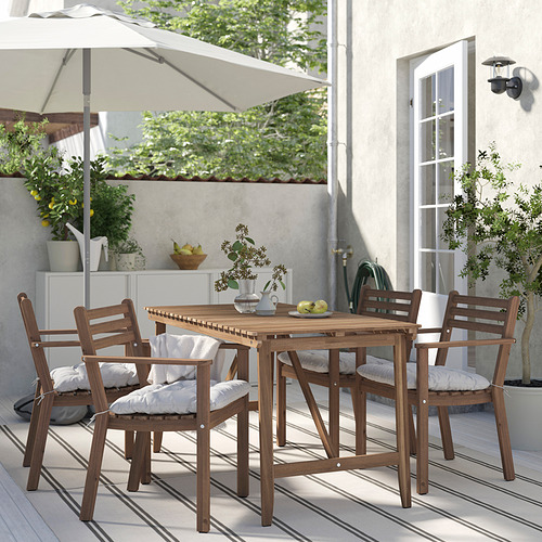 Pequeño juego de comedor al aire libre con 4 sillas y mesa de madera marrón. Los cojines son blancos.