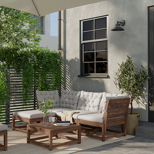 Moderno salón al aire libre con muebles de madera, cojines grises y plantas en macetas, que brindan un área de patio acogedora y elegante.