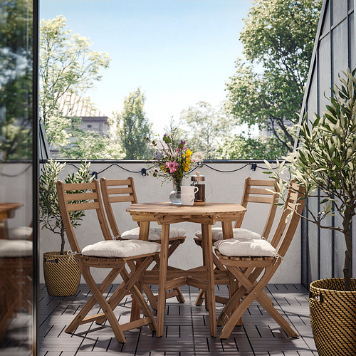 Acogedor balcón con mesa de madera, sillas y guirnaldas de luces para cenar al aire libre.