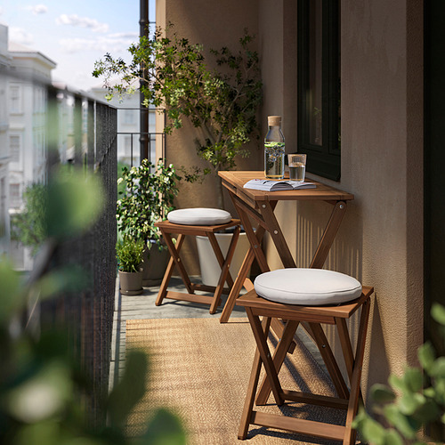 Pequeño balcón de madera con cojines blancos, plantas y un libro.