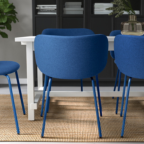 Tres modernas sillas azules con patas metálicas y mesa con estructura blanca. Ideal para cenar, con cómodos asientos tapizados.