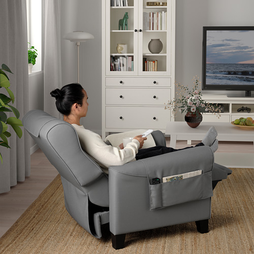 Mujer relajada en el sillón reclinable MAREN, viendo la televisión, con el taburete extendido.