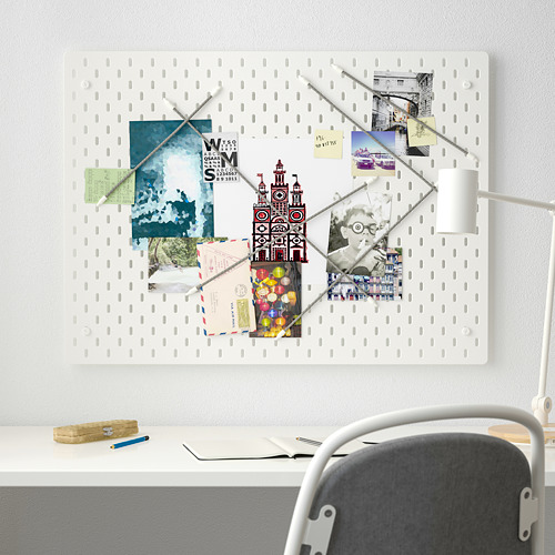 Tablero perforado blanco SKÅDIS con notas y fotos, más grande que el escritorio y la silla.