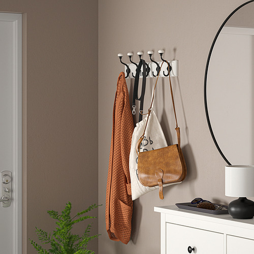Estante LANDKRABBA negro con 5 ganchos, que sujeta suéter naranja, bolso y correas. Al lado de la cómoda y el espejo.