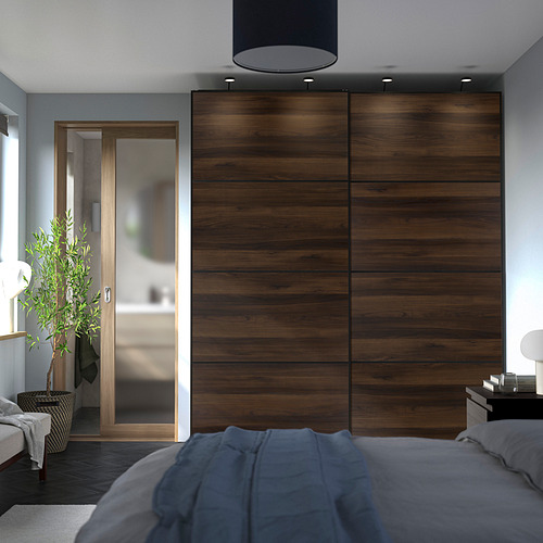 Modern bedroom with large dark wood-effect sliding closet doors, grey bedding, and a potted plant. Wardrobe towers over bed.