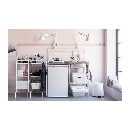 Cocina pequeña y organizada con muebles blancos, fregadero de acero inoxidable y lámparas ajustables.